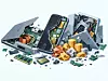 Zerlegte Computerhardware mit Goldmünzen, Chips und Platinen auf hellem Hintergrund.