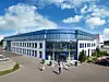 Außenansicht des Pollin Electronic Centers in Pförring mit weißer Gebäudefassade, einer großen blau gerahmten Glasfront am Haupteingang und dem Schriftzug „Electronic Center“.