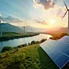 Scenic landscape eco-friendly energy tech. Wind turbines stand tall alongside solar panels near river. Green fields, hills surround area. Sunset paints sky in warm hues. Sustainable energy production