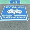 A sign for an EV quick charger on the floor of a rooftop parking lot at an AEON Shopping Mall