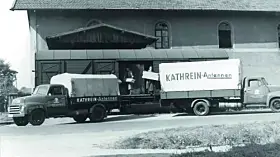 schwarz-weiß Foto eines Autos mit Anhänger. Auf dem Anhänger steht Kathrein-Antennen
