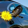Gelbe Blume steckt in einer Tanköffnung eines Autos
